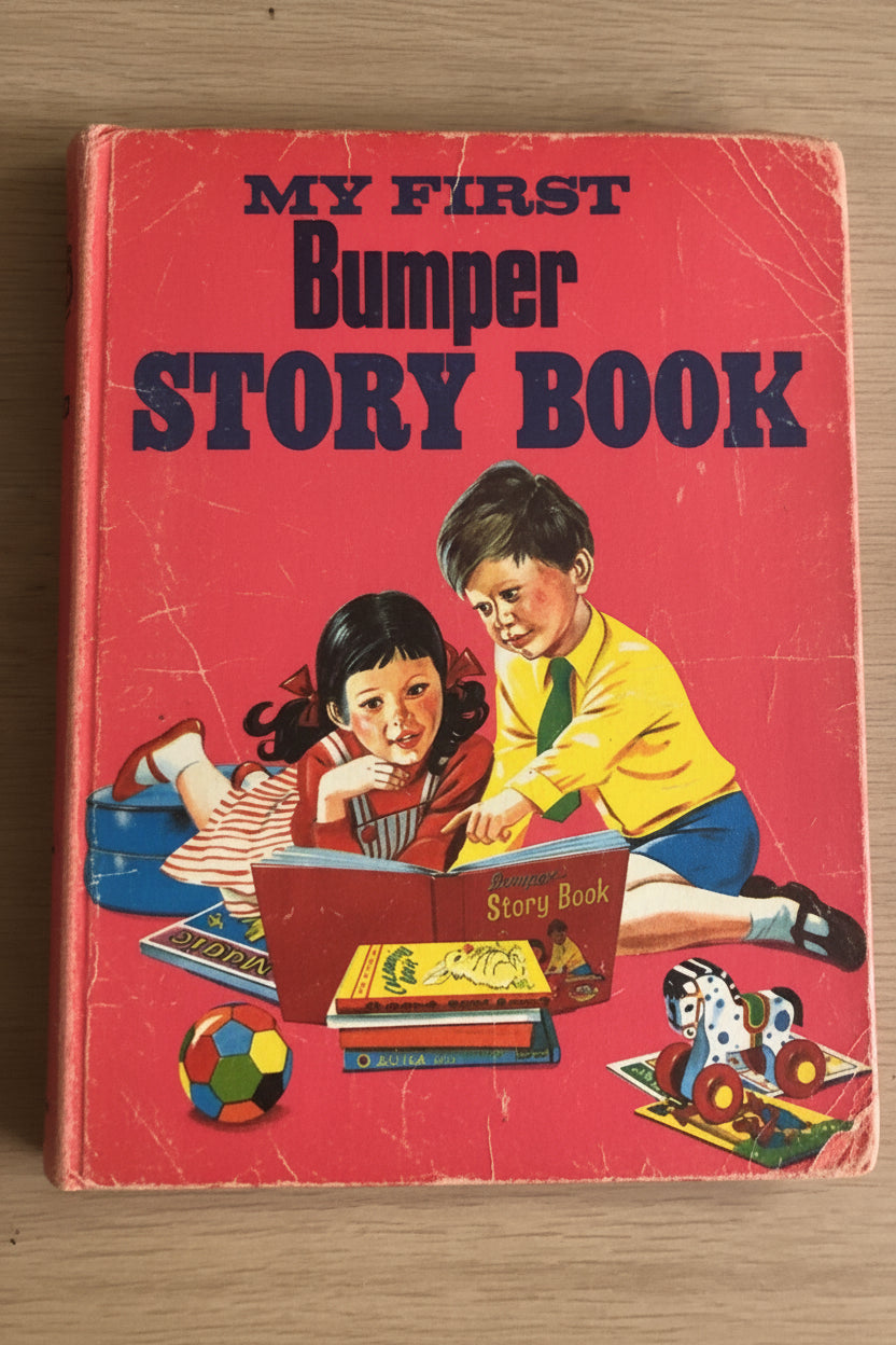 A vintage children's book titled 'My First Bumper Story Book' with a bright pink cover, photographed on a light wood surface. The cover features an illustration of a boy and girl reading, with toy cars and a ball near the bottom.